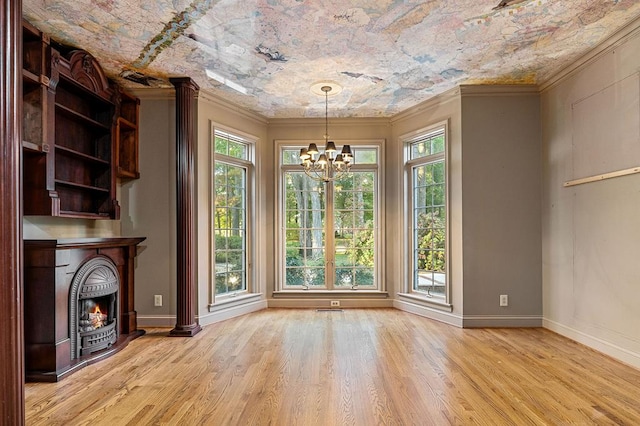 unfurnished dining area featuring baseboards, an inviting chandelier, a lit fireplace, crown molding, and light wood-type flooring