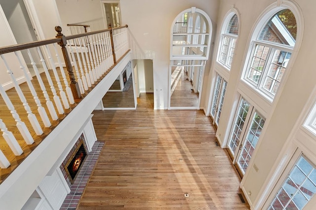 foyer entrance featuring a high ceiling, a fireplace, wood finished floors, and baseboards