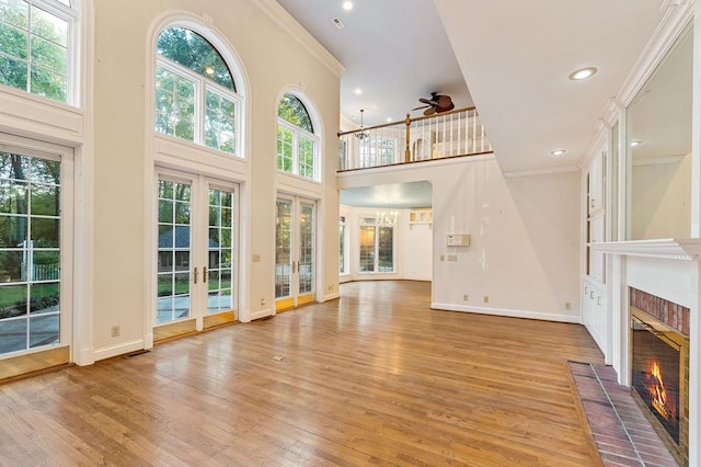 unfurnished living room featuring ornamental molding, light wood finished floors, a brick fireplace, and baseboards