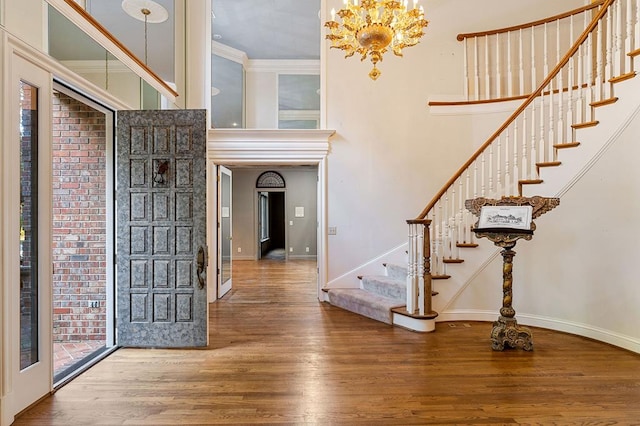 entrance foyer featuring stairway, a towering ceiling, baseboards, and wood finished floors