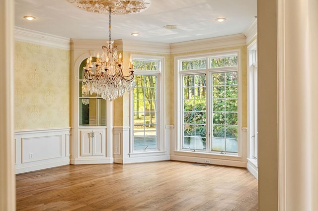 doorway to outside with ornamental molding, wainscoting, a decorative wall, and wood finished floors