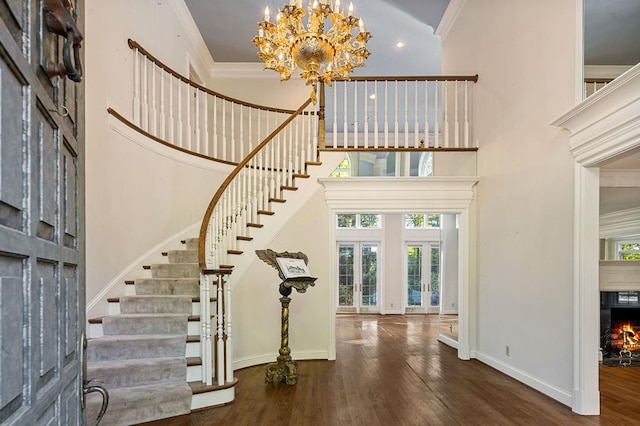 entrance foyer with dark wood finished floors, stairway, ornamental molding, a warm lit fireplace, and baseboards