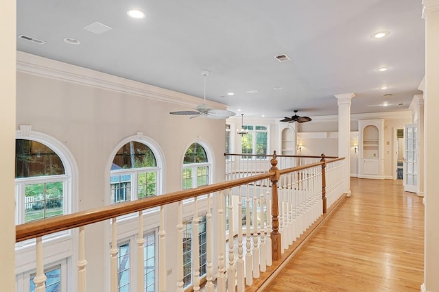 hall with visible vents, crown molding, light wood finished floors, and ornate columns