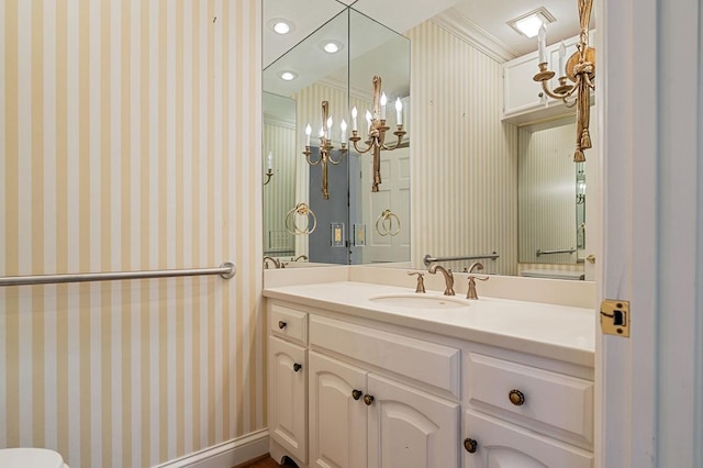 bathroom featuring ornamental molding, vanity, and wallpapered walls