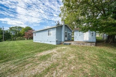 rear view of house featuring crawl space, an outbuilding, and a yard