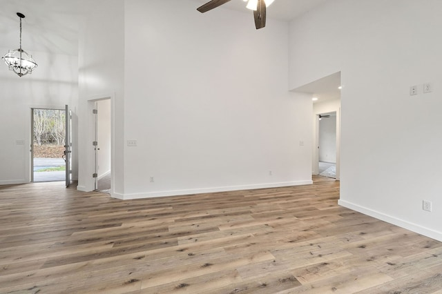 empty room with a towering ceiling, light wood finished floors, and baseboards