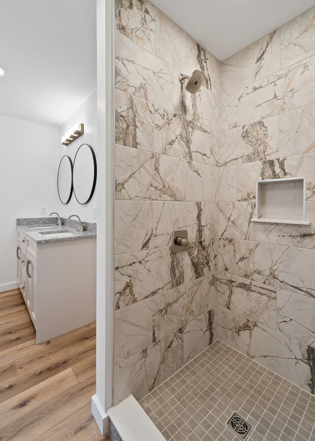 bathroom featuring tiled shower, vanity, and wood finished floors