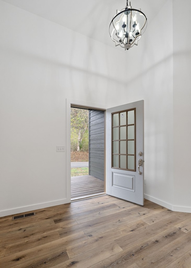 entrance foyer with light wood-style floors, baseboards, visible vents, and an inviting chandelier