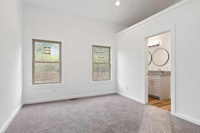 unfurnished bedroom with light colored carpet, multiple windows, visible vents, and baseboards