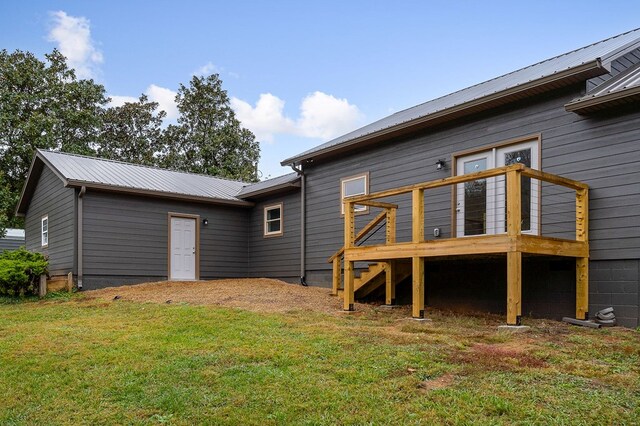 back of house with a deck, metal roof, and a lawn