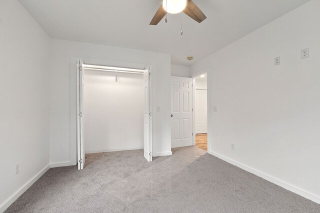 unfurnished bedroom with a ceiling fan, a closet, light carpet, and baseboards