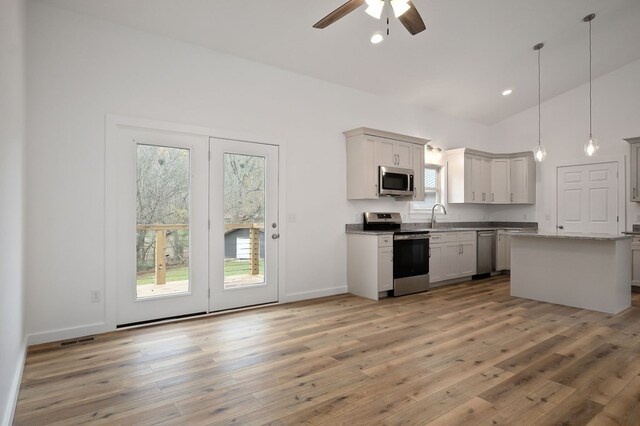 kitchen with stainless steel appliances, a wealth of natural light, decorative light fixtures, and a sink