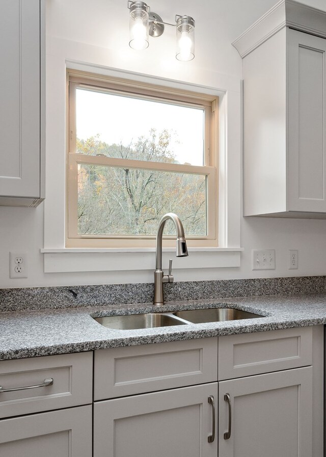 kitchen featuring a sink, a wealth of natural light, and light stone countertops