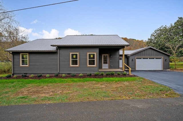 view of front facade with metal roof, a porch, a detached garage, crawl space, and a front lawn