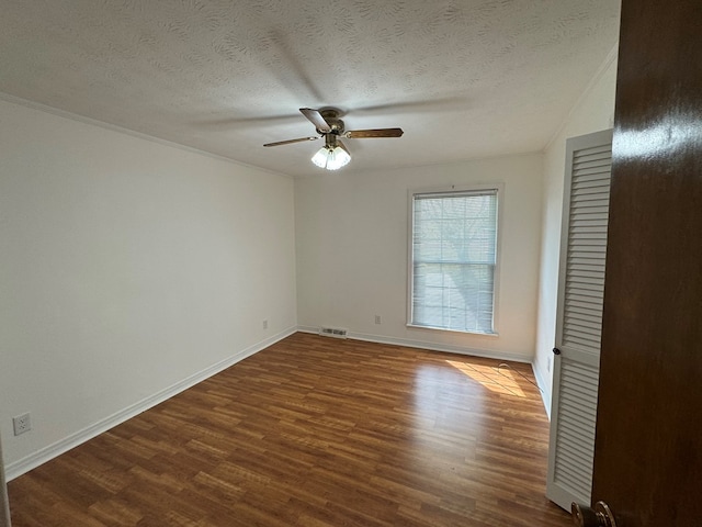 unfurnished room featuring baseboards, visible vents, dark wood finished floors, ceiling fan, and a textured ceiling