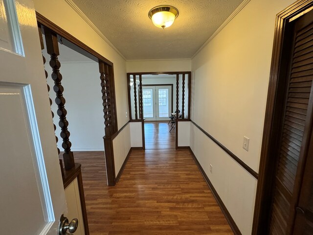 hall with dark wood-style floors, a textured ceiling, crown molding, and baseboards