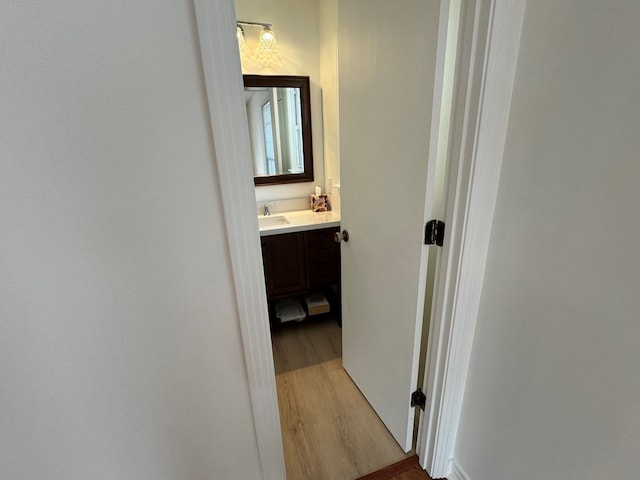 hallway with light wood-style flooring and a sink