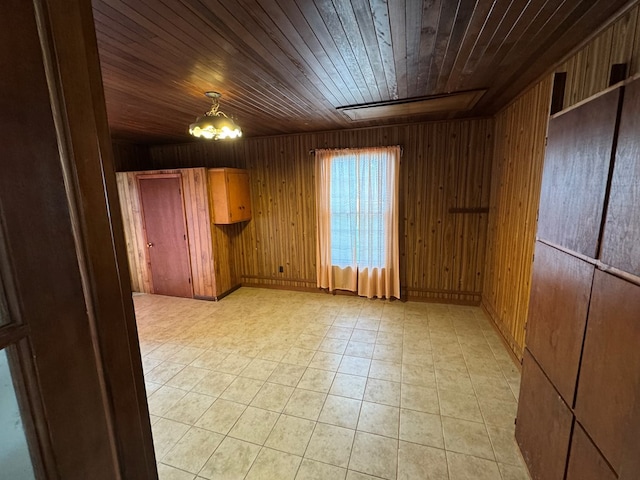 unfurnished room featuring an inviting chandelier, wooden walls, light tile patterned floors, and wood ceiling