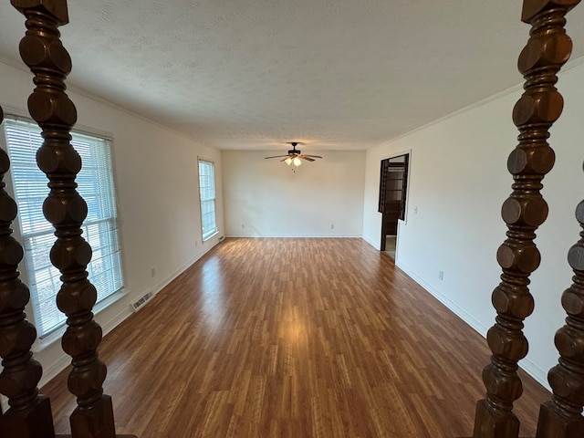 spare room with visible vents, a textured ceiling, wood finished floors, baseboards, and ceiling fan