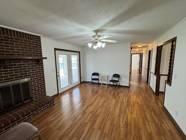 unfurnished living room with ornamental molding, a ceiling fan, a textured ceiling, wood finished floors, and a brick fireplace