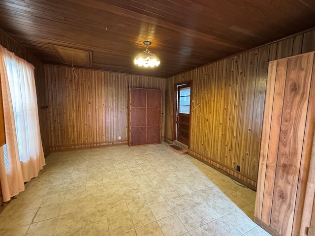 spare room with attic access, wood ceiling, light floors, and wood walls