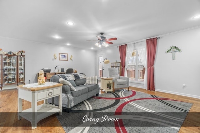 living room featuring baseboards, a ceiling fan, ornamental molding, light wood-type flooring, and recessed lighting