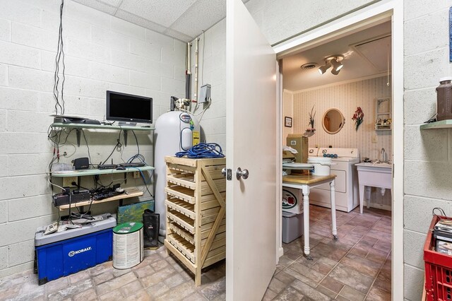 interior space with concrete block wall, washer / clothes dryer, a sink, and a workshop area