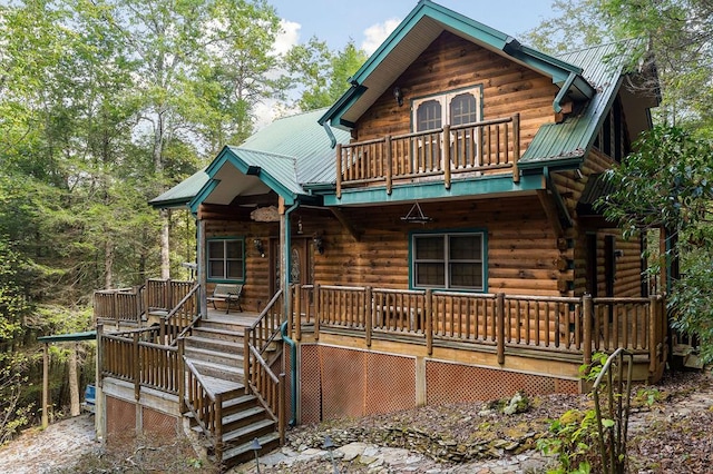 cabin with metal roof, stairway, log siding, and a balcony