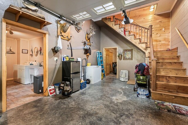 below grade area featuring stairway, washing machine and dryer, freestanding refrigerator, and wooden walls