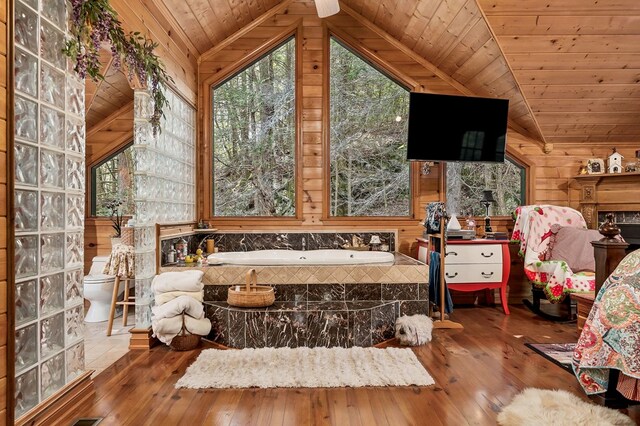 full bath featuring lofted ceiling, wood ceiling, wood finished floors, a garden tub, and wood walls