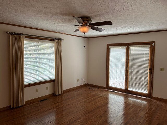 empty room featuring a textured ceiling, dark wood-style flooring, visible vents, and crown molding