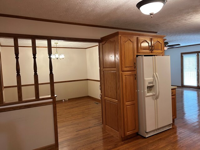 kitchen with white refrigerator with ice dispenser, pendant lighting, light countertops, and dark wood-type flooring