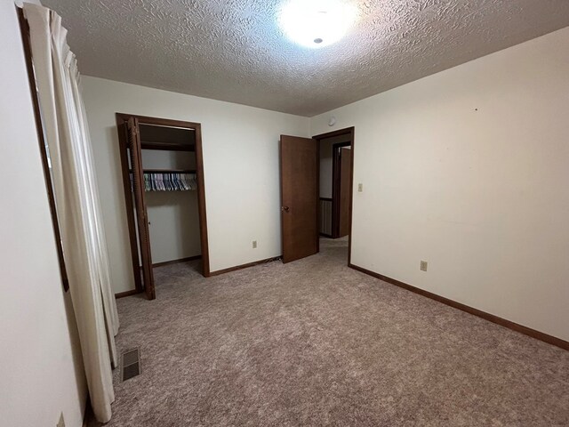 unfurnished bedroom with light carpet, visible vents, and baseboards