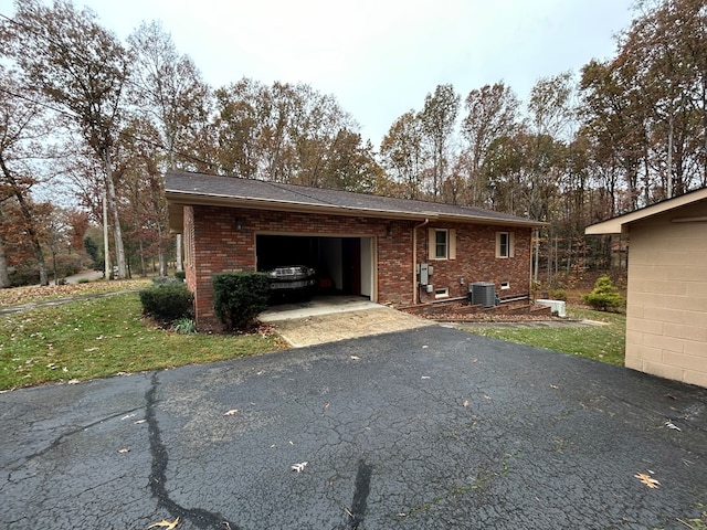 exterior space featuring a garage, aphalt driveway, and brick siding