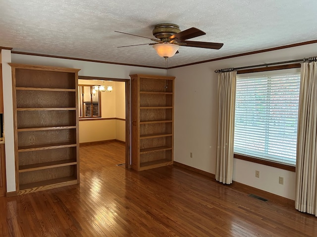 unfurnished room with ceiling fan with notable chandelier, visible vents, dark wood-type flooring, and ornamental molding