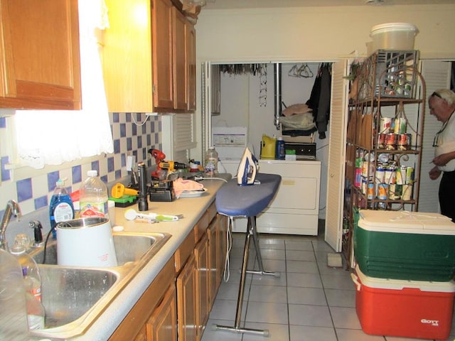 kitchen featuring washer / clothes dryer, light countertops, a sink, and light tile patterned floors