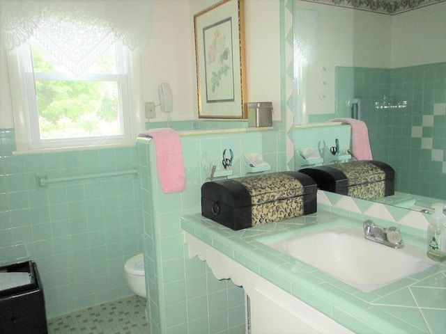 bathroom with toilet, a wainscoted wall, tile walls, and a sink