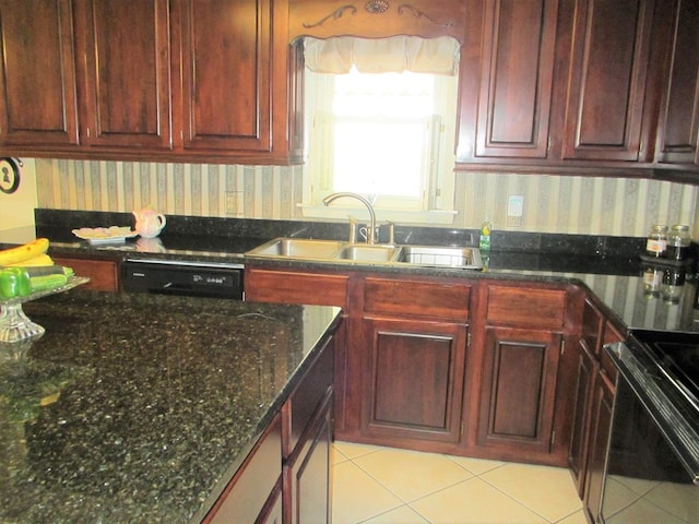 kitchen with a sink, black dishwasher, range, dark stone counters, and wallpapered walls