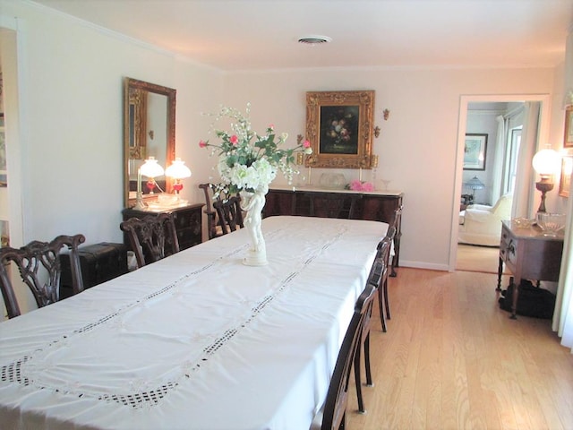 dining space with baseboards, light wood-style flooring, visible vents, and crown molding