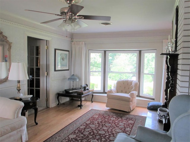 living area with a ceiling fan, a wealth of natural light, visible vents, and wood finished floors