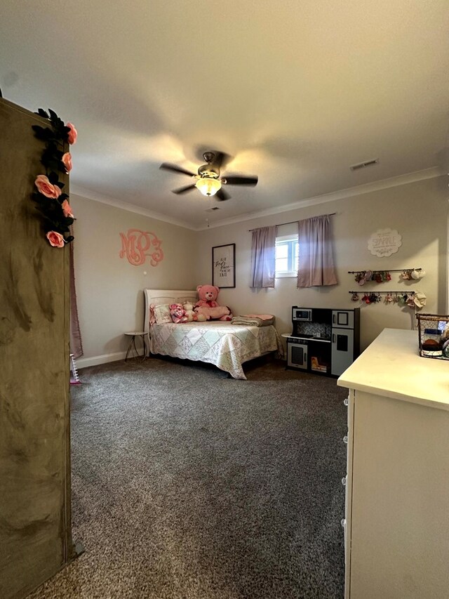 unfurnished bedroom with baseboards, visible vents, ceiling fan, dark colored carpet, and crown molding