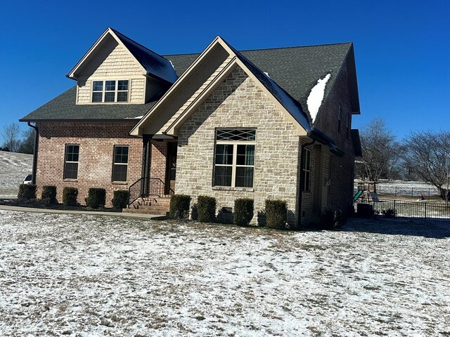 view of front of house with stone siding, fence, and brick siding