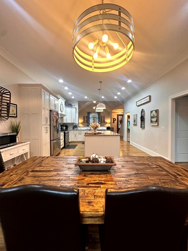 dining room with baseboards, wood finished floors, vaulted ceiling, crown molding, and recessed lighting