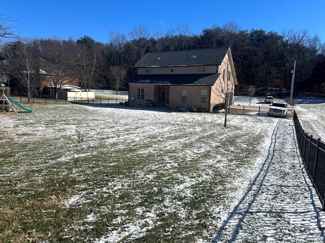 snow covered back of property with brick siding and fence