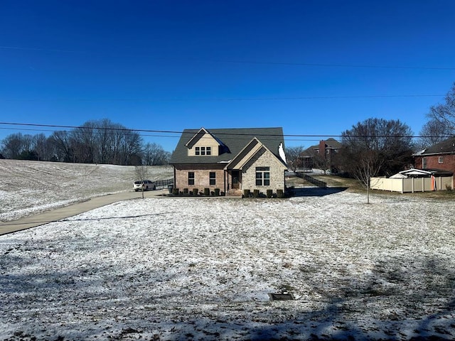 view of front of house featuring stone siding and fence