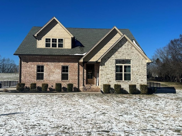 view of front facade with brick siding and roof with shingles