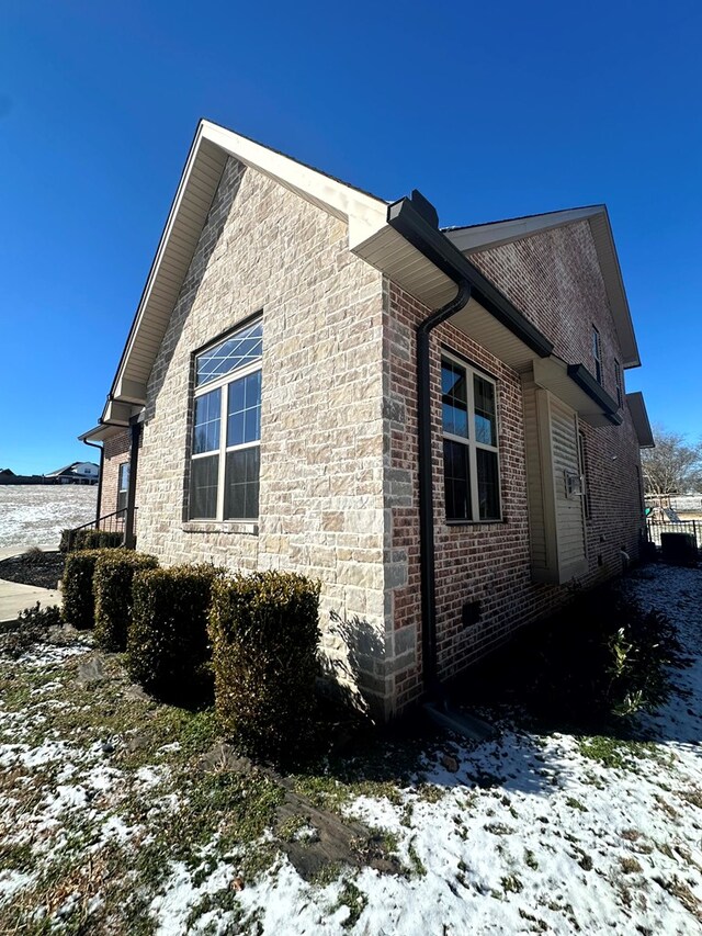 snow covered property with brick siding