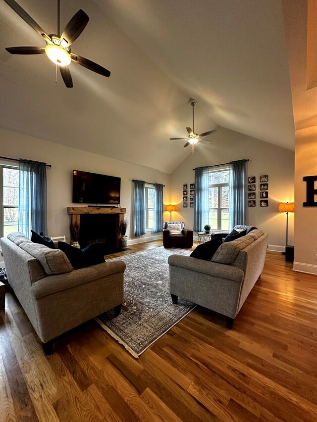 living area with a fireplace, lofted ceiling, ceiling fan, wood finished floors, and baseboards