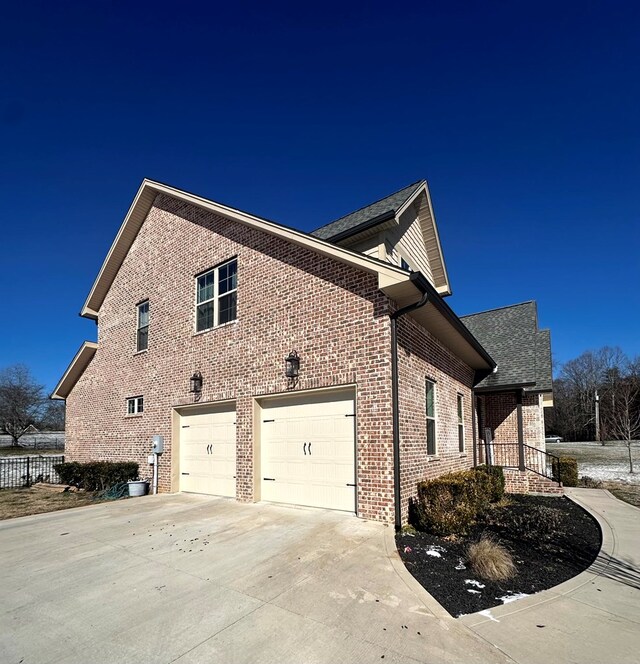 view of home's exterior with a garage, concrete driveway, and brick siding