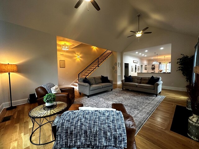 living area with visible vents, baseboards, a ceiling fan, dark wood-style floors, and stairway